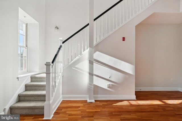 stairway with wood-type flooring and a high ceiling