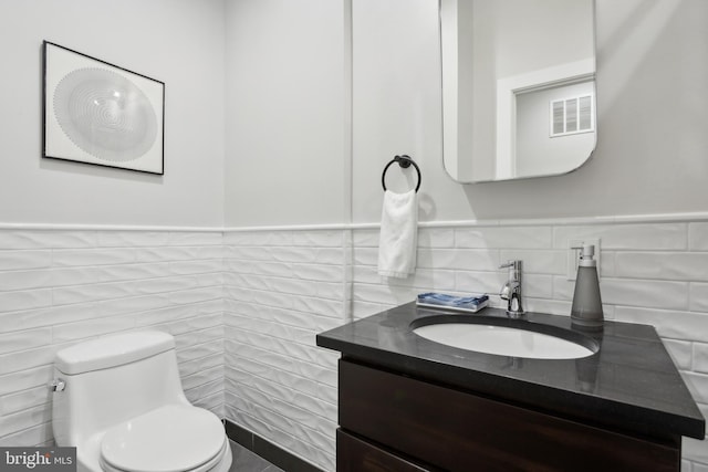 bathroom with tile walls, vanity, and toilet