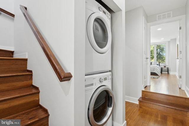 clothes washing area featuring stacked washer / dryer and hardwood / wood-style flooring