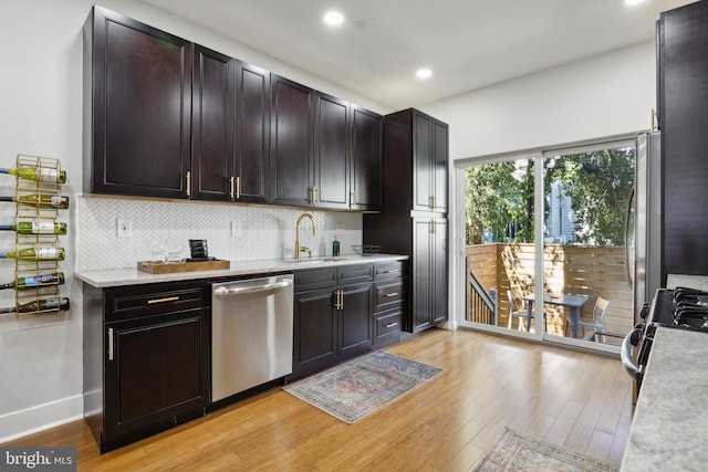 kitchen featuring stainless steel appliances, backsplash, sink, and light hardwood / wood-style flooring