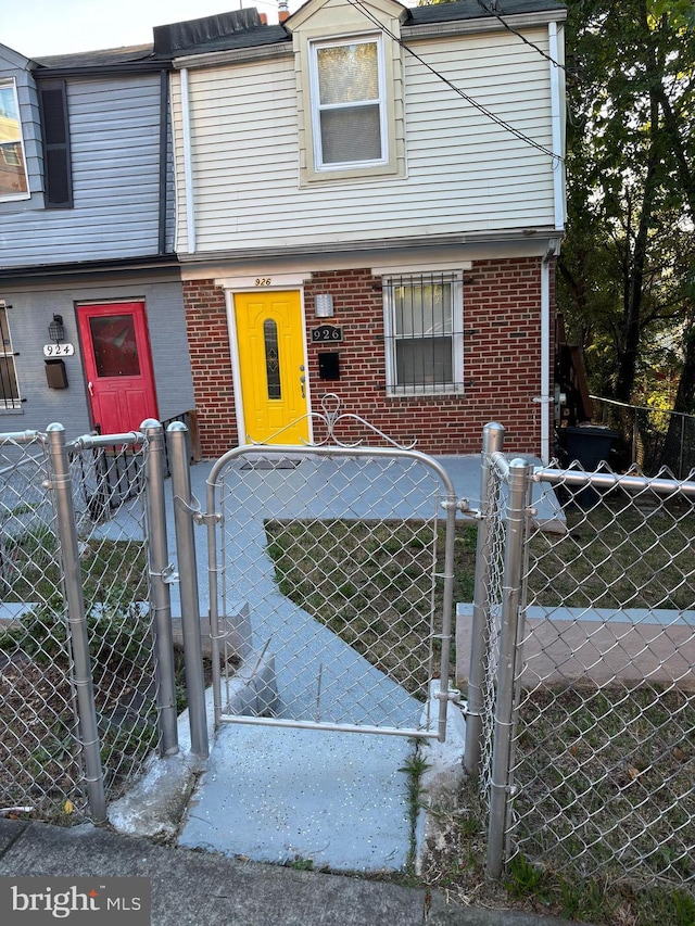 multi unit property featuring brick siding, a fenced front yard, and a gate