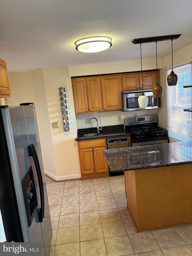 kitchen featuring dark stone countertops, pendant lighting, stainless steel appliances, sink, and light tile patterned flooring