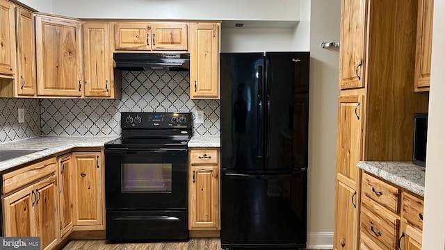 kitchen with black appliances, backsplash, and light stone counters