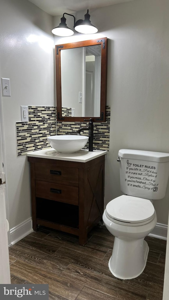 bathroom featuring decorative backsplash, wood-type flooring, vanity, and toilet