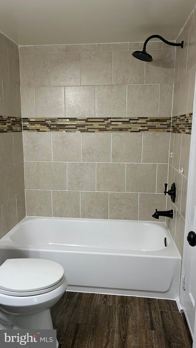 bathroom with tiled shower / bath, hardwood / wood-style flooring, and toilet