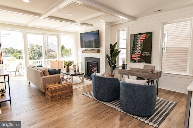 living room with coffered ceiling, a wealth of natural light, and light hardwood / wood-style floors