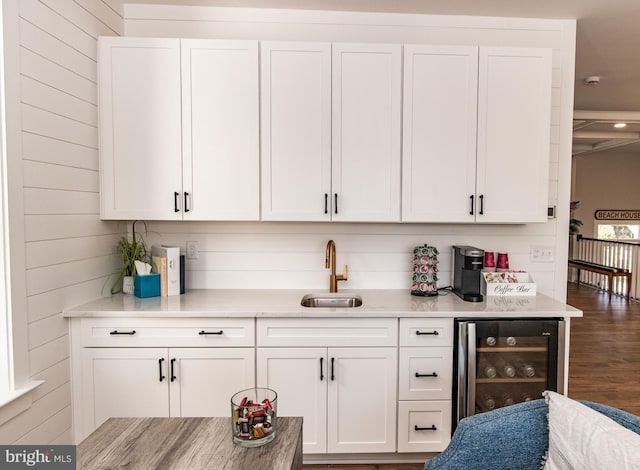 bar with dark hardwood / wood-style floors, beverage cooler, sink, white cabinetry, and wooden walls