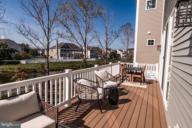 wooden terrace featuring a water view and outdoor lounge area