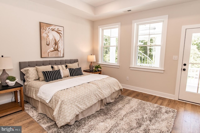 bedroom with access to exterior and hardwood / wood-style floors