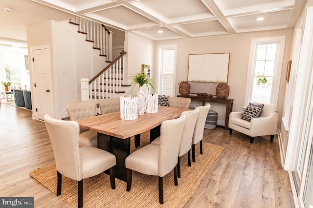 dining area featuring light hardwood / wood-style flooring, coffered ceiling, and beamed ceiling