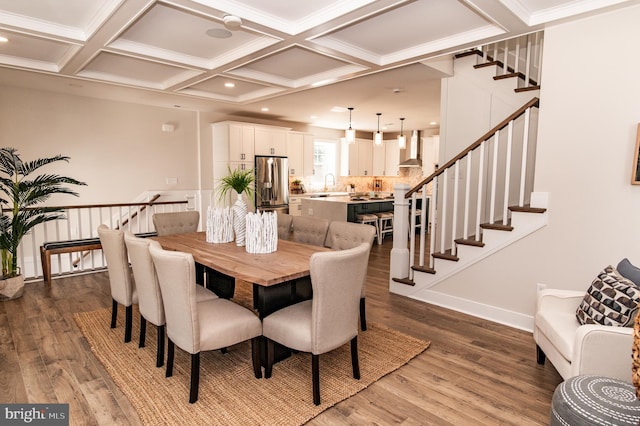 dining area featuring crown molding, dark wood-type flooring, coffered ceiling, and sink