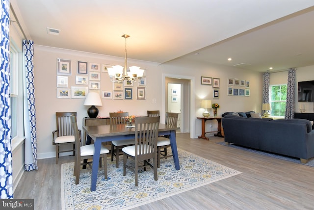 dining area featuring crown molding, light wood-type flooring, and a chandelier