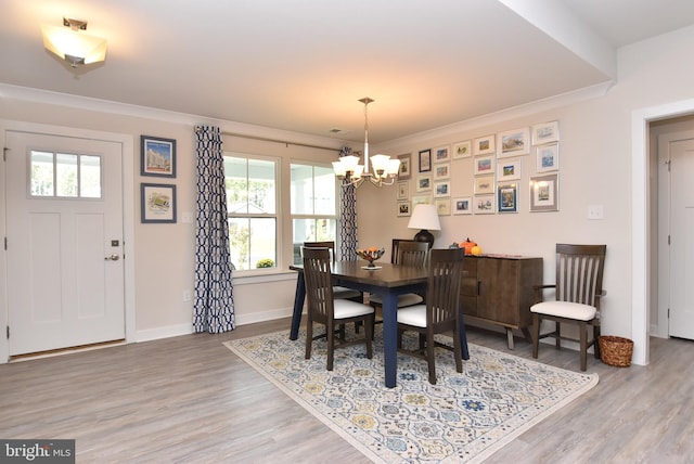 dining area with plenty of natural light, hardwood / wood-style flooring, ornamental molding, and a chandelier