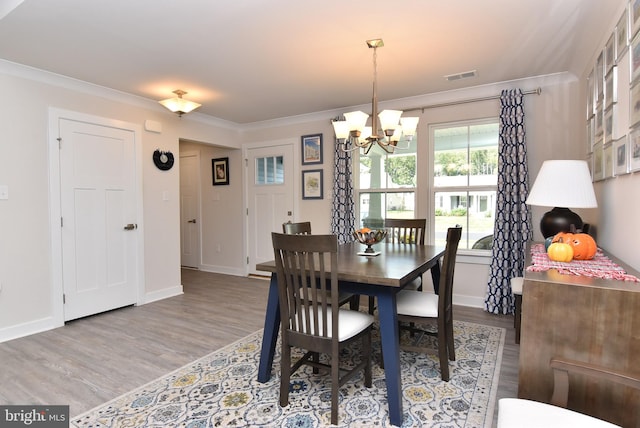 dining space with ornamental molding, hardwood / wood-style flooring, and a notable chandelier