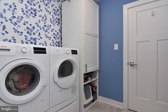 clothes washing area with cabinets, washing machine and clothes dryer, and light tile patterned flooring