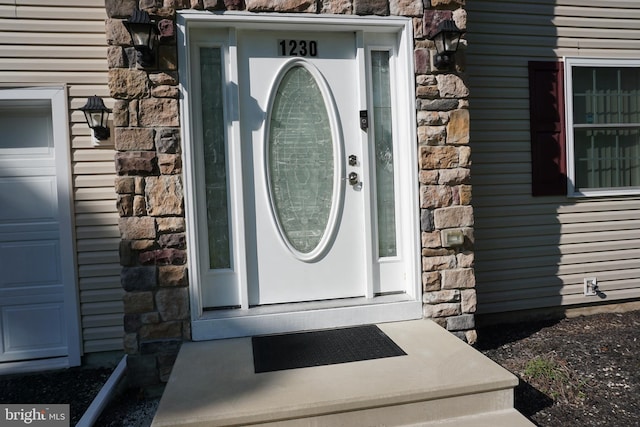 entrance to property featuring a garage and stone siding