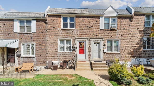 view of property with brick siding, cooling unit, and a patio