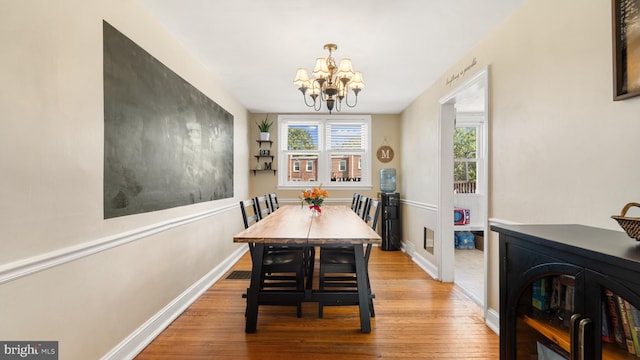 dining space featuring wood-type flooring and an inviting chandelier