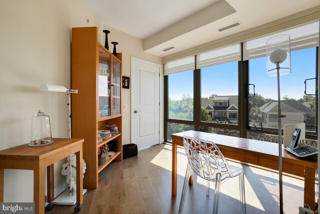 home office with light hardwood / wood-style flooring and a wall of windows