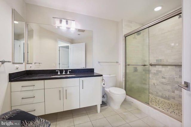 bathroom featuring tile patterned flooring, vanity, toilet, and a shower with door