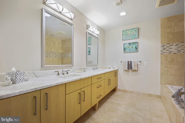 bathroom featuring tile patterned flooring, vanity, and tiled tub