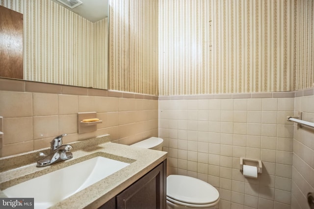 bathroom featuring tile walls, vanity, and toilet