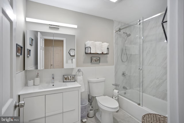 full bathroom featuring shower / bath combination with glass door, vanity, tile walls, and toilet