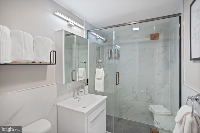 bathroom featuring vanity, tile walls, a shower with shower door, and toilet