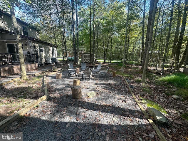 view of yard featuring a storage shed, an outdoor fire pit, and a deck