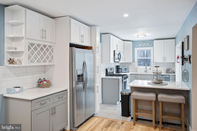 kitchen featuring white cabinets, gray cabinets, appliances with stainless steel finishes, and light hardwood / wood-style floors