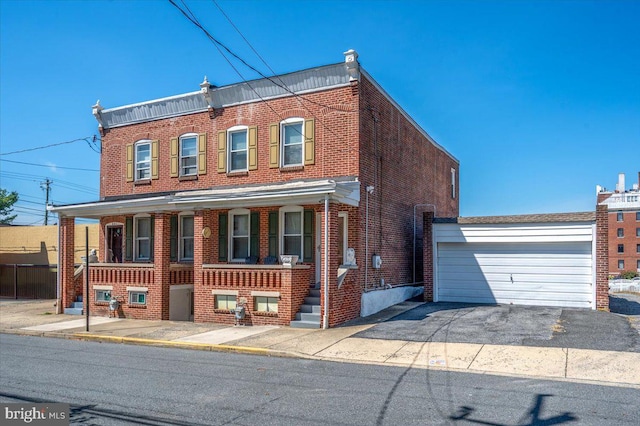 townhome / multi-family property with a detached garage, brick siding, and covered porch