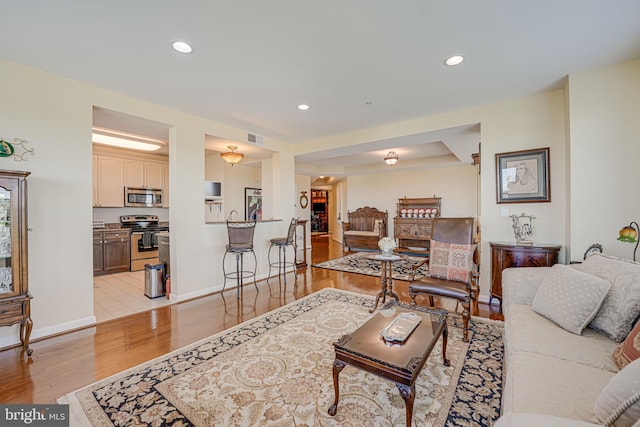 living area with visible vents, recessed lighting, light wood-type flooring, and baseboards