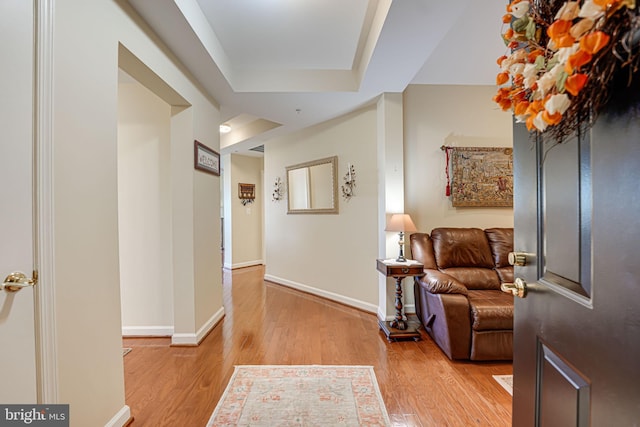 corridor featuring baseboards and light wood finished floors