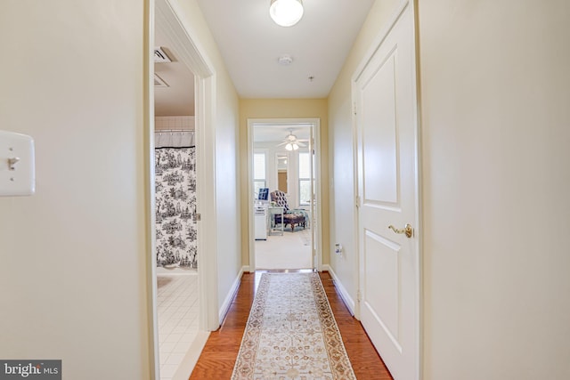 corridor featuring wood finished floors and baseboards