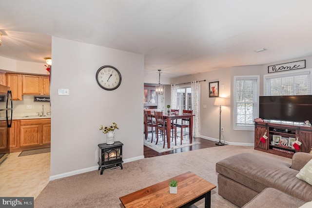 carpeted living room with an inviting chandelier, a wood stove, and sink