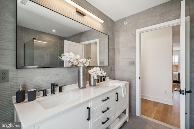 bathroom with wood-type flooring, vanity, and tile walls