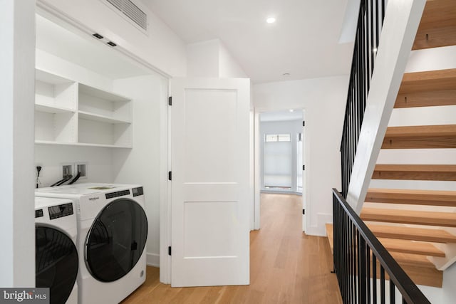 laundry area featuring separate washer and dryer and light hardwood / wood-style floors