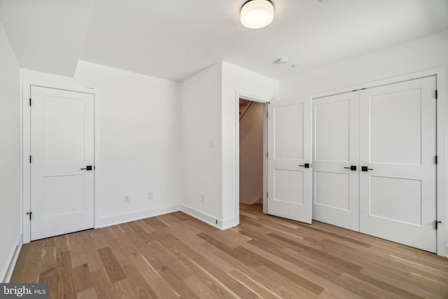 unfurnished bedroom with light wood-type flooring and a closet