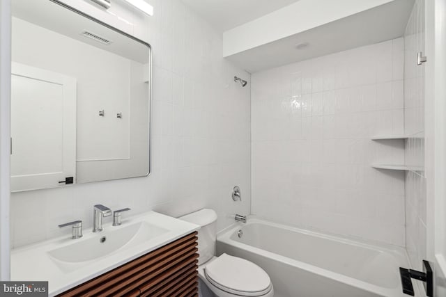 full bathroom featuring tile walls, backsplash, vanity, tiled shower / bath, and toilet