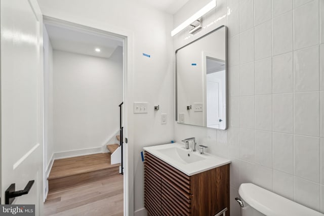 bathroom featuring tile walls, vanity, hardwood / wood-style floors, and toilet