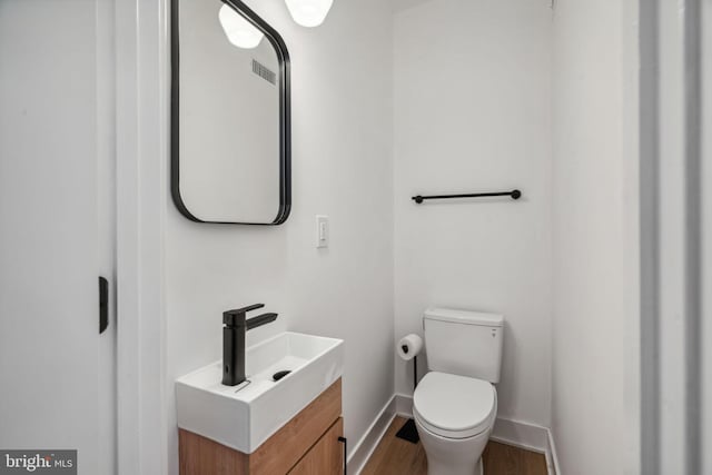 bathroom with hardwood / wood-style floors, vanity, and toilet