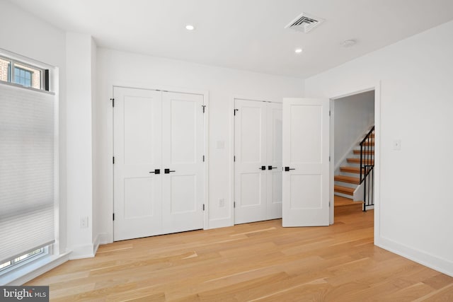 unfurnished bedroom featuring light hardwood / wood-style flooring and multiple closets