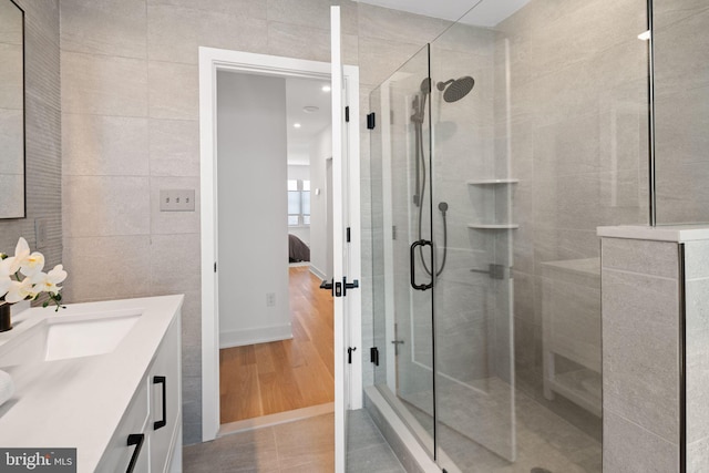 bathroom featuring vanity, tile walls, hardwood / wood-style floors, and an enclosed shower