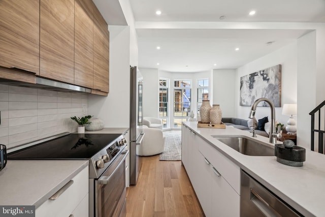 kitchen featuring white cabinetry, sink, light hardwood / wood-style flooring, and stainless steel appliances