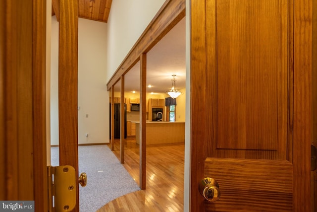 corridor featuring lofted ceiling and light hardwood / wood-style flooring