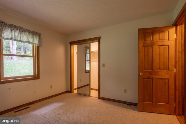 unfurnished bedroom with a closet, light colored carpet, and a textured ceiling