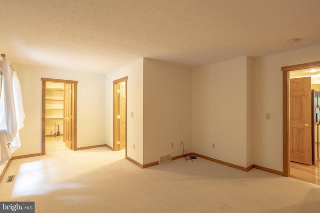 carpeted empty room with a textured ceiling