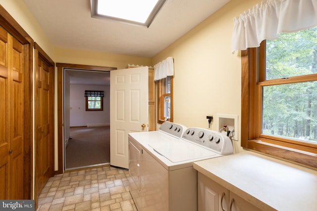 clothes washing area featuring washing machine and dryer and cabinets