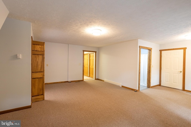 carpeted spare room with a textured ceiling and a baseboard radiator