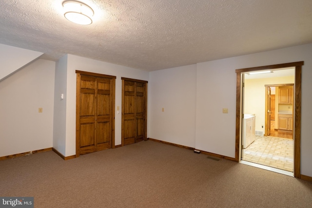 unfurnished bedroom with carpet, a textured ceiling, and ensuite bath